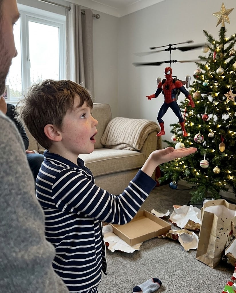 Boy hovering a Spider-Man FlyHero Pro above his open palm by a Christmas tree